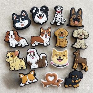 Puede incluir: Una colección de coloridos dijes con temática de perros en varias razas, incluyendo un dálmata, Shiba Inu y Corgi. Cada dije es un diseño detallado de estilo caricatura con colores vibrantes y expresiones juguetonas. Estos dijes son probablemente para zapatos o accesorios.