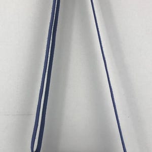 May include: A blue and white patterned crossbody bag with a red and white stripe detail. The bag has a blue zipper and a blue circle logo.