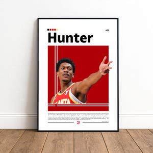 May include: A framed poster featuring a basketball player in a red and yellow jersey. The poster has the name "Hunter" in large black letters, with the number 12. The background is red with white vertical lines.