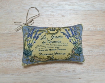 May include: A lavender-scented sachet with a yellow background and blue trim. The sachet features a vintage-style illustration of lavender flowers and the text "Le Jardin de Lavande, Route du Monte-Ventoux, Provence-France".