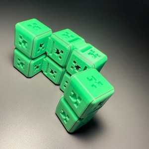 May include: A green 3D printed puzzle with a unique design. The puzzle is made up of multiple cubes that are connected together. The cubes have a textured surface and are arranged in a way that creates a geometric pattern.