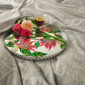Könnte beinhalten: Ein silbernes Tablett mit einer verspiegelten Oberfläche, die mit einem handgemalten Blumendesign in Rosa-, Rot- und Grüntönen verziert ist. Eine Tasse Kaffee steht auf dem Tablett, zusammen mit drei rosafarbenen Rosen.