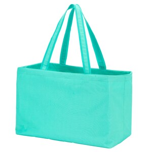 Op de afbeelding: Een turquoise draagtas met een rechthoekige vorm en twee sets handvatten. De tas is gemaakt van een effen gekleurde stof. De handvatten hebben dezelfde kleur als de tas.