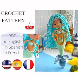 May include: A crochet pattern PDF document featuring a mermaid doll with long curly turquoise hair, a tan complexion, and a light green tail. The doll holds a small golden harp. Text includes CROCHET PATTERN, PDF, and PDF in English, Spanish, and French.
