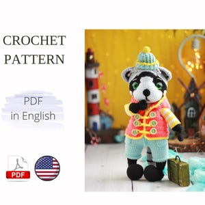 May include: Crochet pattern PDF in English for a cute raccoon amigurumi toy wearing a blue and yellow hat, a pink and yellow jacket, and blue pants. The raccoon is holding a suitcase.