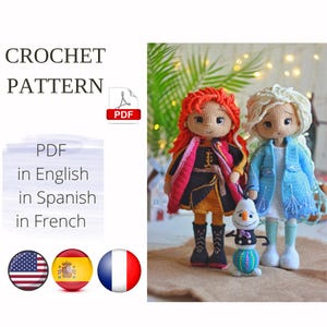 Op de afbeelding: Haakpatroon PDF in het Engels, Spaans en Frans voor het maken van twee poppen, een met rood haar en een zwart en oranje outfit, en de andere met blond haar en een blauwe outfit. De poppen houden een kleine sneeuwpop vast.