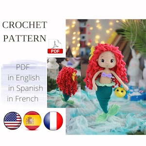 Pode incluir: Padrão de crochê PDF para uma boneca sereia de cabelo ruivo com cauda verde e um peixe amarelo. O padrão está disponível em inglês, espanhol e francês.