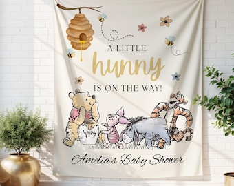 May include: Cream-colored baby shower backdrop featuring Winnie the Pooh and friends. The banner includes a beehive, bees, and the text "A Little Hunny Is On The Way!" with the name "Amelia" below. The design is whimsical and celebratory.