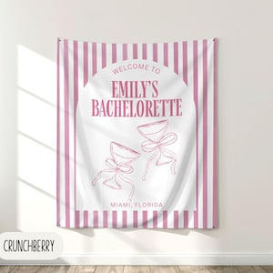 Puede incluir: Un tapiz a rayas rosas y blancas con el texto "Welcome to Emily's Bachelorette" y dos copas de champ&aacute;n con lazos. Tambi&eacute;n se incluye el texto "Miami, Florida".