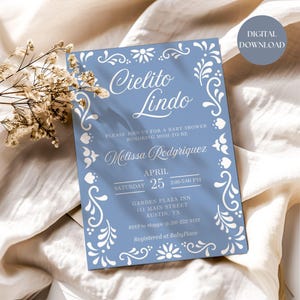 May include: A blue baby shower invitation with white floral designs and the text "Cielito Lindo" in a decorative font. The invitation includes the date, time, and location of the shower, as well as the name of the mom-to-be, Melissa Rodriguez.