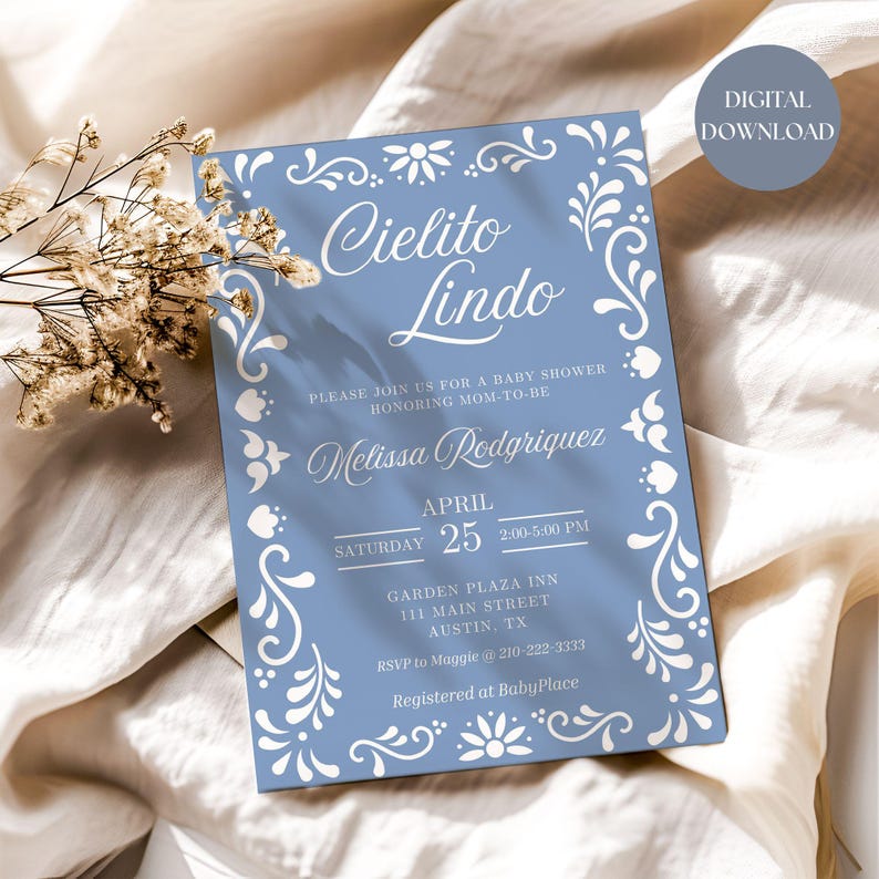 May include: A blue baby shower invitation with white floral designs and the text "Cielito Lindo" in a decorative font. The invitation includes the date, time, and location of the shower, as well as the name of the mom-to-be, Melissa Rodriguez.
