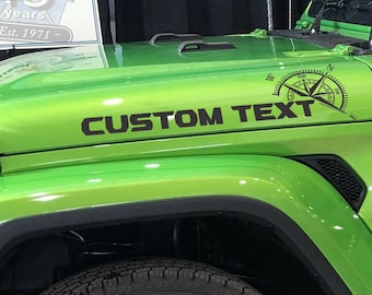 Puede incluir: Jeep Wrangler verde con una calcomanía de brújula negra y el texto "CUSTOM TEXT" en el capó.