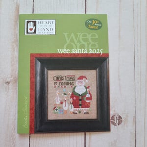May include: A framed cross-stitch featuring Santa Claus, geese, and the text "CHRISTMAS IS COMING." The artwork is set against a neutral background, with a green and red border. The cover reads "wee santa 2025" and "Our 30th annual Santa!"