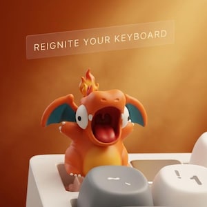 May include: An orange and blue figurine of a cartoon dragon with its mouth open, perched on a white keyboard. The figurine has a flame on its head. The text "REIGNITE YOUR KEYBOARD" is displayed above the figurine.