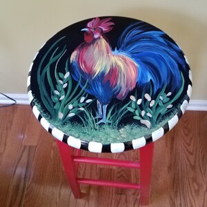May include: A red painted stool with a black and white striped base. The top of the stool is painted black with a colorful rooster illustration.