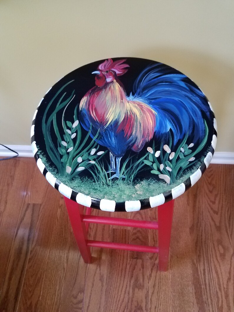 May include: A red painted stool with a black and white striped base. The top of the stool is painted black with a colorful rooster illustration.