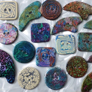 May include: A selection of decorative buttons in diverse shapes and sizes. The buttons display a range of colours and patterns, including swirls, speckles, and abstract designs. Some are square, round, or uniquely shaped, with two or four holes for sewing.