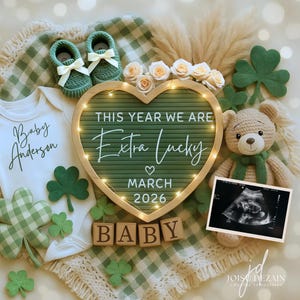 Könnte beinhalten: Eine Babyankündigung mit grünem und weißem Thema. Sie enthält einen weißen Body, grüne Babyschuhe, ein herzförmiges Schild mit Text, einen Teddybären und ein Ultraschallbild. Auf dem Schild steht "THIS YEAR WE ARE Extra Lucky MARCH 2026 BABY".