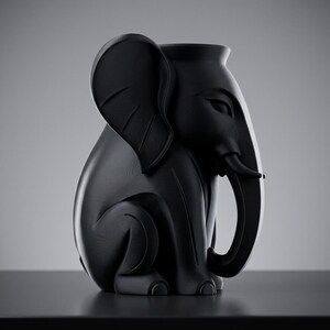 K&ouml;nnte beinhalten: Eine schwarze, elefantenf&ouml;rmige Vase mit glatter, matter Oberfl&auml;che. Die Vase hat einen detaillierten R&uuml;ssel, gro&szlig;e Ohren und eine sitzende Haltung. Das Design ist modern und skulptural, geeignet f&uuml;r die Inneneinrichtung.