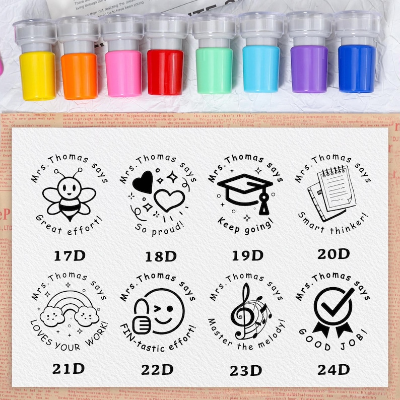 May include: A set of colorful self-inking stamps with various designs and phrases, including a bee, hearts, a graduation cap, and a notebook. Each stamp has a different color ink, such as yellow, orange, pink, red, green, blue, and purple.