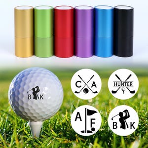 May include: A golf ball on a tee with a golfer silhouette and the initials "B K". Six colourful metal tubes in gold, green, red, purple, blue, and black. Four circular designs with golf-related graphics.