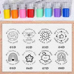 May include: A set of eight colorful self-inking stamps with clear plastic tops. The stamps have various designs with the text "Mrs. Thomas says" and encouraging messages like "Keep going!" and "Good Job!"