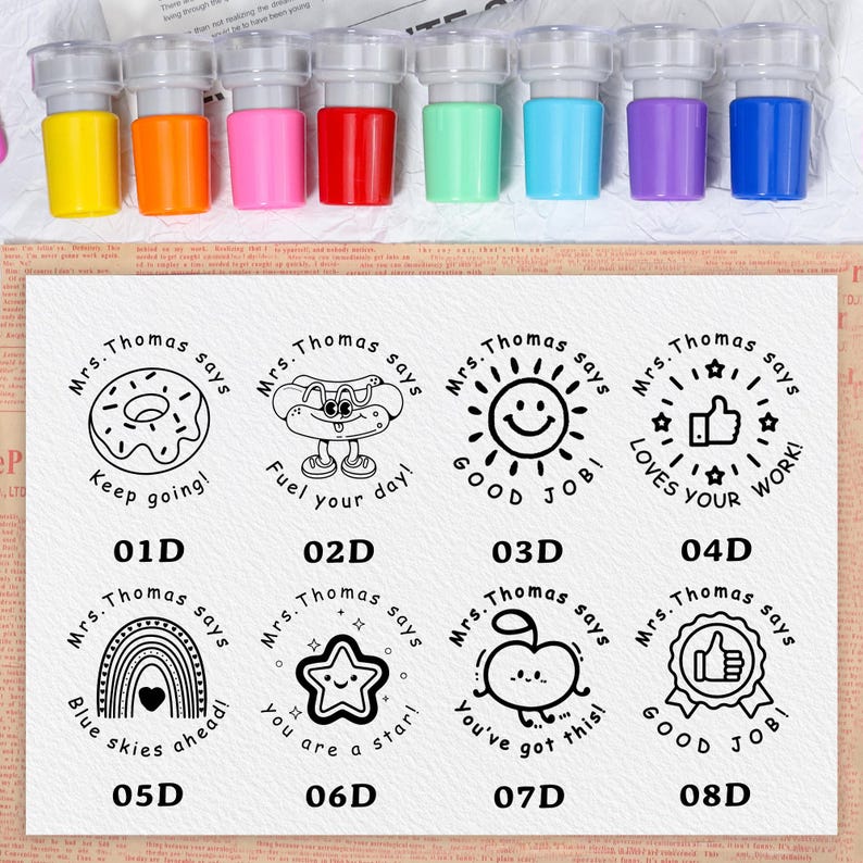 May include: A set of eight colorful self-inking stamps with clear plastic tops. The stamps have various designs with the text "Mrs. Thomas says" and encouraging messages like "Keep going!" and "Good Job!"