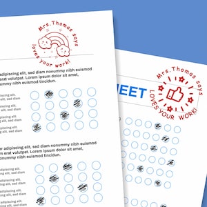 May include: Two white sheets of paper with blue circles and text. One sheet has a red stamp that says "Mrs. Thomas says loves your work!" with a rainbow and clouds. The other sheet has a red thumbs up stamp.