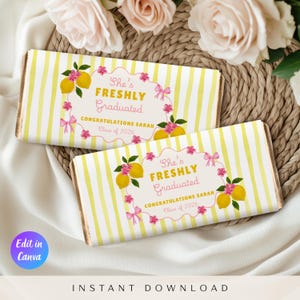 Op de afbeelding: Twee chocoladereepverpakkingen met gele en witte strepen. Elke verpakking heeft de tekst "She's Freshly Graduated" met "Congratulations Sarah Class of 2026". Het ontwerp bevat citroenen, roze bloemen en strikken.