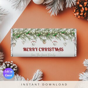 Könnte beinhalten: Eine weihnachtliche Schokoriegelverpackung mit dem Text "MERRY CHRISTMAS" in Burgunderrot. Die Verpackung ist mit Tannenzweigen, Ornamenten und dem Text "Love, The Jones Family" verziert.