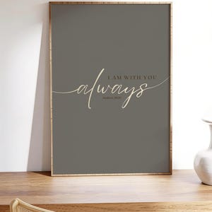 Könnte beinhalten: Ein rechteckiger Wandkunstdruck in einem dünnen Holzrahmen mit dunkelgrauem Hintergrund. Der Text "I AM WITH YOU" steht in einer serifenlosen Schrift über dem Wort "always" in Schreibschrift, darunter steht "Matthew 28:20".