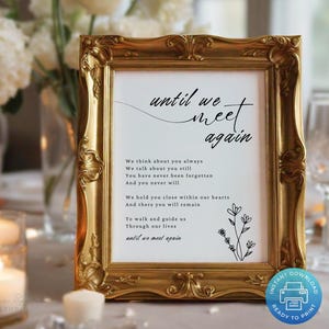 May include: A framed print with the words "until we meet again" in elegant script. The gold frame surrounds a white background with a poem and floral illustration. Candles and flowers are in the background.