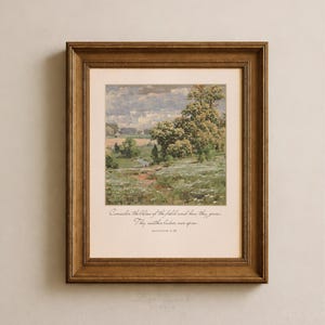 May include: A framed wall art print featuring an impressionist landscape painting of a meadow with trees and a cloudy sky. Below the artwork, the text reads: Consider the lilies of the field and how they grow. They neither labor nor spin. MATTHEW 6:28.