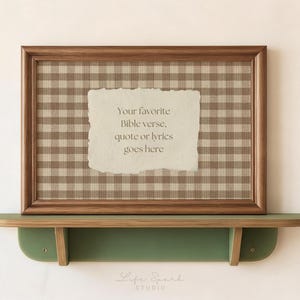 Könnte beinhalten: Ein rechteckiger Holzrahmen mit einem beigefarbenen und braunen Vichy-Karo-Hintergrund und einem mittigen Papiereinsatz mit abgerissenen Kanten, der den Text enthält: Your favorite Bible verse, quote or lyrics goes here, auf einem grünen Holzregal.