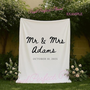 mockup of a white tapestry banner hanging near some trees and neuatful ivory flowers perfect to use for mockups that are selling tapestry backdrops or signs for weddings, bachelorette trips or bridal showers