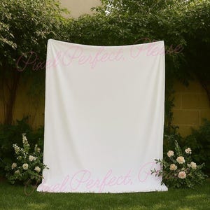 mockup of a white tapestry banner hanging near some trees and neuatful ivory flowers perfect to use for mockups that are selling tapestry backdrops or signs for weddings, bachelorette trips or bridal showers