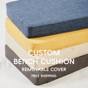May include: Stack of four custom bench cushions in shades of blue, yellow, cream, and gray. Each cushion has a square shape with a removable cover. The text "CUSTOM BENCH CUSHION REMOVABLE COVER" is displayed on the image.