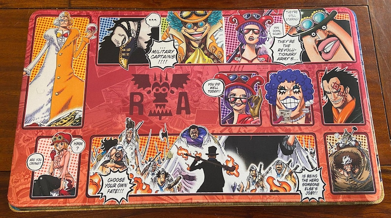 May include: A rectangular playmat featuring colorful illustrations of anime characters. The design includes comic-style panels with text like "MILITARY CAPTAINS" and "CHOOSE YOUR OWN FATE!!!". The dominant colors are red, orange, and white.