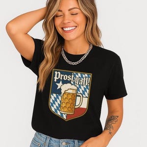 May include: Black t-shirt with a graphic featuring a beer stein and the text "Prost y'all!" in a shield design. The shield has a blue and white checkered pattern, a white star, and red accents. The beer stein is filled with foamy beer.