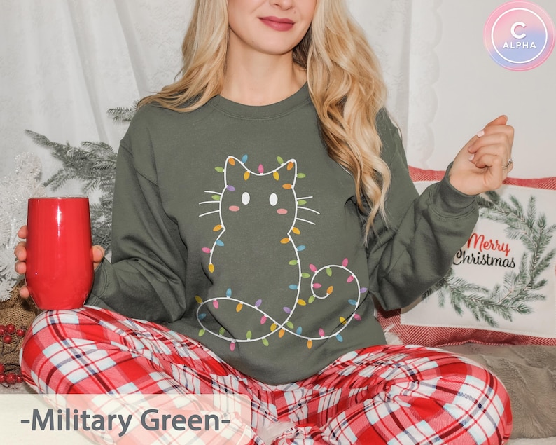 Cozy military green sweatshirt with a whimsical cat outline wrapped in colorful lights. Perfect for enjoying Christmas festivities in comfort and style.