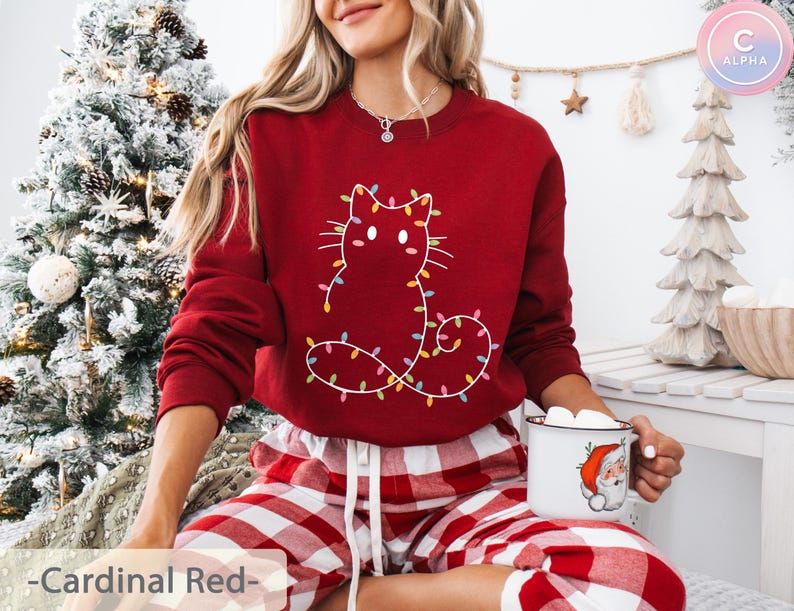 Charming cardinal red sweatshirt featuring a festive cat outline with Christmas lights. A cute and cheerful addition to holiday parties and winter celebrations.