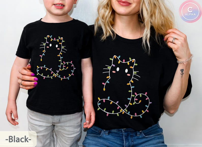 Matching black T-shirts for adults and kids featuring a festive cat outline with colorful Christmas lights. Perfect for family photos and holiday memories.