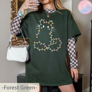 Festive forest green T-shirt with a cute cat outline decorated with Christmas lights. Ideal for holiday gatherings, bringing a subtle Christmas vibe for cat lovers.