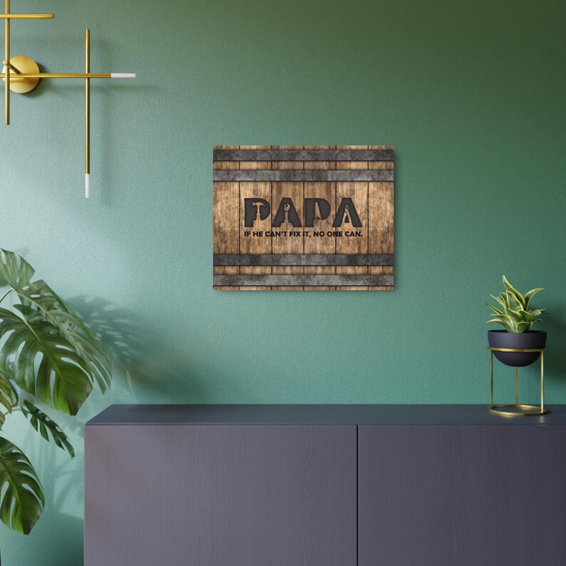 Each letter in the bold word PAPA includes the silhouette of a hand tool as part of the letter.  Beneath the word PAPA is the phrase “If he can’t fix it, no one can.” The background looks like aged vertical boards similar to a flattened oak barrel. At the top and bottom are aged metal strips. This is a perfect gift for anyone’s husband, dad, stepdad, grandpa, or favorite male friend who has tools and knows who to fix things. NOTE: This is a flat metal sign, not real wood or metal.
