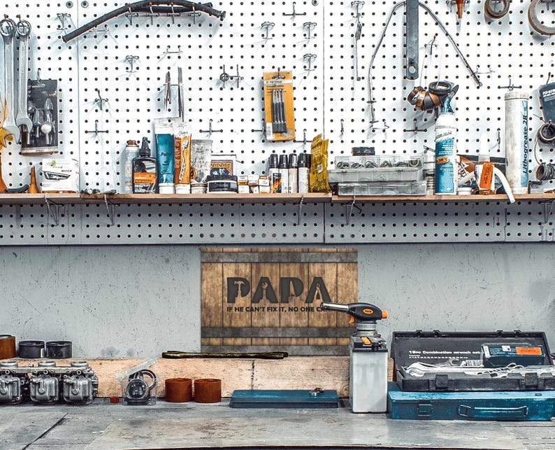 Each letter in the bold word PAPA includes the silhouette of a hand tool as part of the letter.  Beneath the word PAPA is the phrase “If he can’t fix it, no one can.” The background looks like aged vertical boards similar to a flattened oak barrel. At the top and bottom are aged metal strips. This is a perfect gift for anyone’s husband, dad, stepdad, grandpa, or favorite male friend who has tools and knows who to fix things. NOTE: This is a flat metal sign, not real wood or metal.