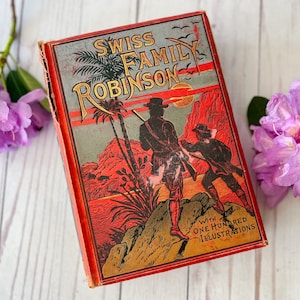 May include: A vintage hardcover book titled "Swiss Family Robinson" with red, gold, and black illustrations. The book cover features a jungle scene with two figures in the foreground. The text "With One Hundred Illustrations" is printed at the bottom of the cover.