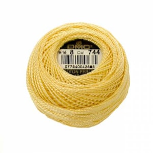 May include: A skein of DMC embroidery floss in a pale yellow color. The label reads "DMC Perle 8 Col. 744" and includes a barcode.