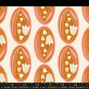 May include: A white background with a repeating pattern of oval-shaped designs. Each oval is filled with a brown background and a white floral design. The flowers are stylized lily of the valley flowers with a pink outline.