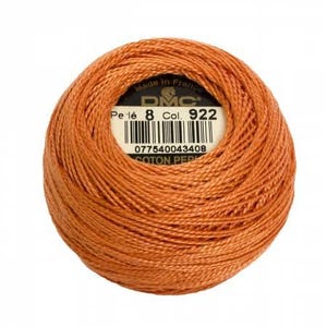 May include: A ball of DMC embroidery floss in color 922, a burnt orange shade. The label reads "Pe. 16 8 Col. 922" and includes a barcode. The label also says "Made in France" and "DMC".