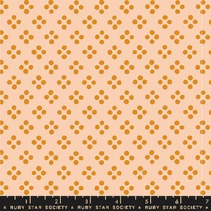 May include: A fabric with a repeating pattern of four orange dots arranged in a square on a light peach background. The fabric has a ruler at the bottom with the text "RUBY STAR SOCIETY".